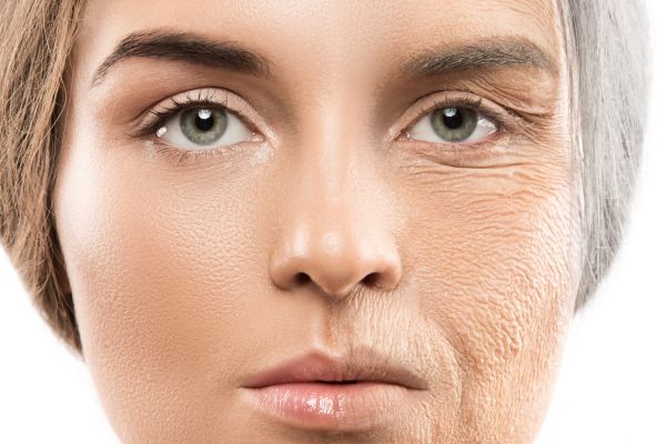 Close-up of a person’s face; the left side appears young, with blonde hair and firm, healthy skin, while the right side features grey hair and skin with significant wrinkles and signs of aging.